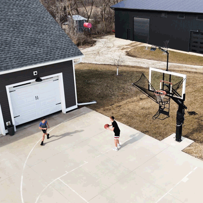 Two players shooting on Dr. Dish IC3 Basketball Shot Trainer in driveway